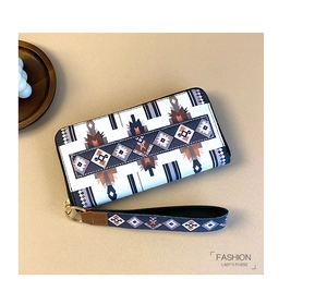 Detail of white Aztec pattern long wallet featuring geometric totem and wristlet strap