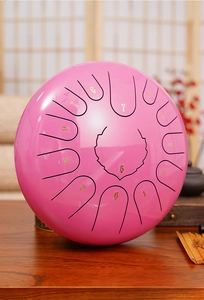 Pink 8-note steel tongue drum with numbered scales on a wooden table with zen decor