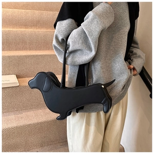 Detail view of a black dachshund-shaped faux leather shoulder bag worn by a model