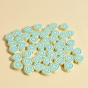 Gros plan de perles de cœur en argile polymère vert clair 10mm pour bijoux DIY