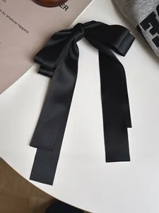 Détail d'un n'ud papillon en satin noir à longs rubans avec texture soyeuse élégante