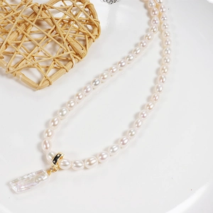 Minimalist freshwater baroque pearl necklace with gold clasp on white ceramic surface