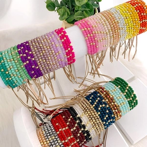 Detail of colorful beaded bracelet set with gold metal accents on white jewelry stand