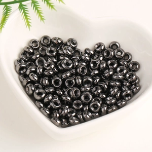 Detailed view of black round wheel beads in a white heart-shaped bowl for DIY jewelry