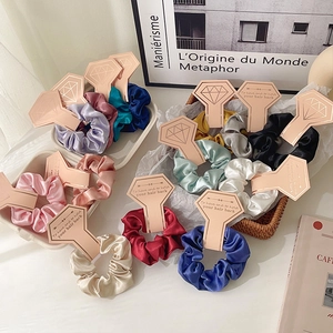 Elegant multi-color satin scrunchies set with paper display cards on a decorative tray