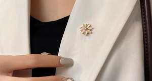 Gros plan d'une broche fleur dorée avec pierre œil de chat et zircon sur revers blanc