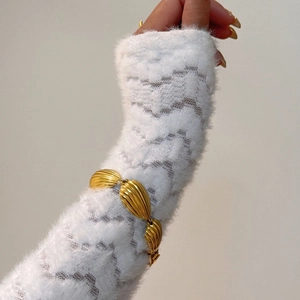 Macro shot of 18k gold plated titanium bracelet with shell textured metal links on a model