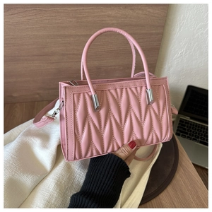 Detailed close-up of a pink pleated handbag featuring diamond quilted texture and silver hardware