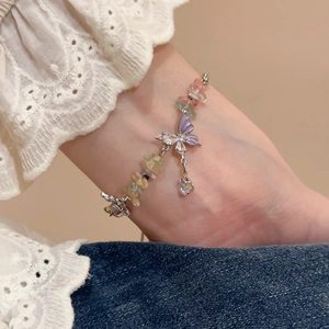 Close-up of hand wearing colorful stone bracelet with a purple zircon butterfly pendant