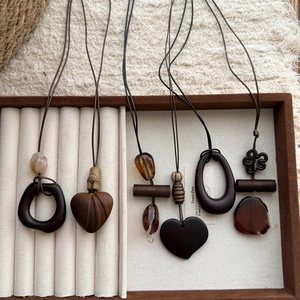 Detailed close-up of retro wood and resin geometric pendants on a velvet jewelry tray