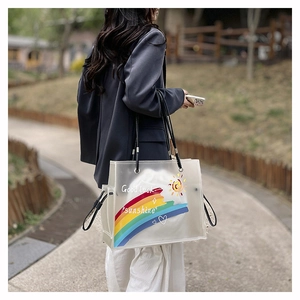 Outdoor shot of a transparent PVC tote bag with rainbow prints and long black straps