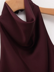 Detail view of burgundy satin halter top hanging on a wooden hanger with silk texture