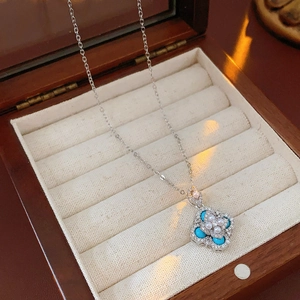 Detailed close-up of clover flower pendant with pearls and turquoise on velvet box