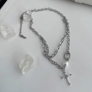 Double-layered cross necklace with pearls and rhinestones on minimalist white crystal background
