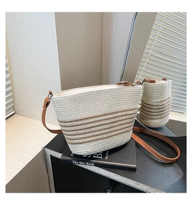 Detail view of striped woven straw crossbody bag with brown leather strap on books