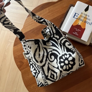Detail of bohemian linen shoulder bag with black and white floral patterns on a wooden table
