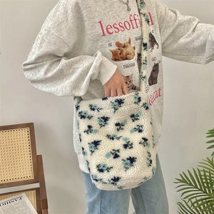 Detail of plush lamb wool bucket bag with blue floral pattern and wide shoulder strap