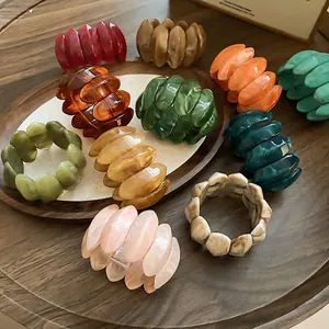 Unique oval acrylic stretch bracelets set in diverse marble colors on wooden tray