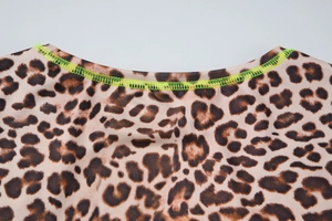 Détail du col à imprimé léopard avec coutures contrastées vert néon et tissu en maille