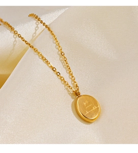 Macro detail of a brushed 18K gold plated oval pendant on soft luxury silk fabric