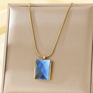 Close-up of blue rectangular glass pendant on a gold snake chain necklace