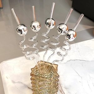 Detail of five spiral straws with silver mirror disco ball decorations in a glass