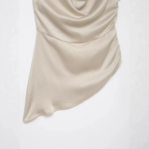Haut dos nu en satin champagne avec ourlet asymétrique et texture soyeuse élégante