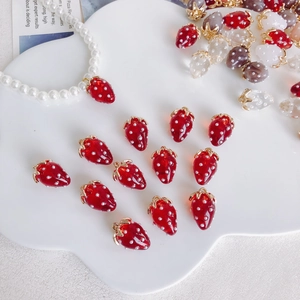 Detailed view of colorful resin strawberry charms with gold metal rings for DIY crafts