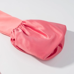 Détail des poignets en satin rose avec plis élégants et texture brillante sur la robe