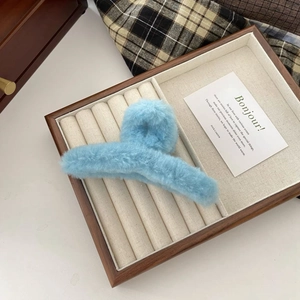 Macro detail of a light blue plush hair claw clip showing the soft and fuzzy texture