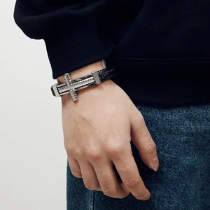 Men's black braided leather bracelet with silver stainless steel cross on model's wrist