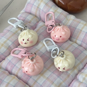Detail of pink and cream dumpling keychains on a checkered mat with plastic D-hooks