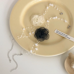 Close-up of three-layer faux pearl necklace with delicate mesh flower on a ceramic plate