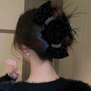 Detail of velvet bow hair claw with sparkling rhinestones and black feather accents