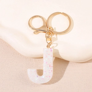 Détail du porte-clés lettre J en résine avec paillettes et anneau en métal doré