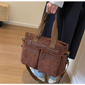 Brown corduroy tote bag shown in hand by model, minimalist style with multi-pocket design