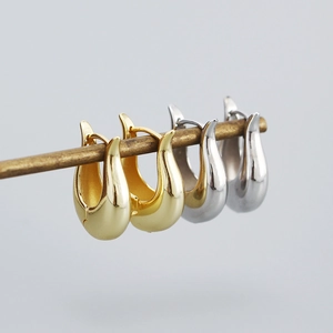 Close-up of gold and silver teardrop earrings hanging on a thin metallic rod