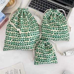 Detailed view of three sizes of beige drawstring pouches with green tulip floral patterns