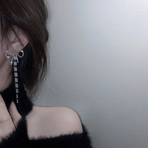 Detail of silver bow tassel earrings with sparkling crystals worn by a model