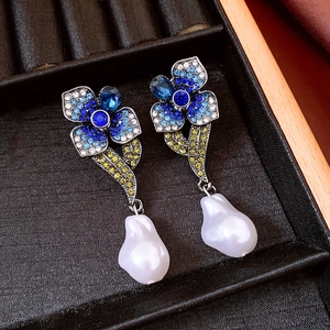 Détail de boucles d'oreilles fleur vintage avec cristaux colorés et perles baroques