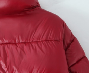 Detail of red shiny puffer jacket showing shoulder seams and quilted glossy fabric texture