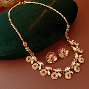 Detail of vintage gold jewelry set with red gems and zircons on green velvet