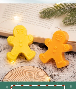 Detail of gingerbread man scented candles in lemon yellow and orange brown on snow base
