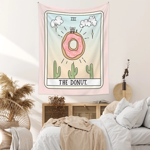 Detail of The Donut Tarot tapestry with cat motif hanging over a cozy bedroom bed