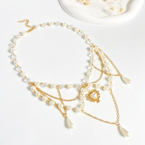 Detail of layered gold necklace with heart pearl pendant and crystal fringe tassels