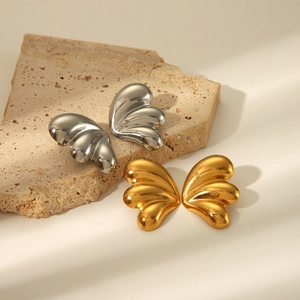 Vue macro des boucles d'oreilles ailes de papillon en or et argent sur socle en pierre