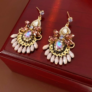 Detail of luxury bohemian crystal tassel earrings with purple gems on wooden box