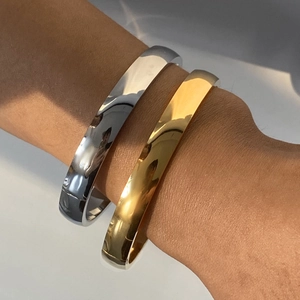 Polished gold and silver stainless steel C-shape bangles worn on a model wrist