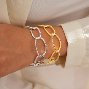 Close-up of gold and silver large oval chain bracelets with hammered texture on wrist