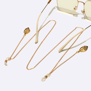 Detailed view of golden metal eyewear chain with delicate leaf pendants and non-slip loops